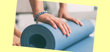 Une femme pliant un tapis d’exercice.