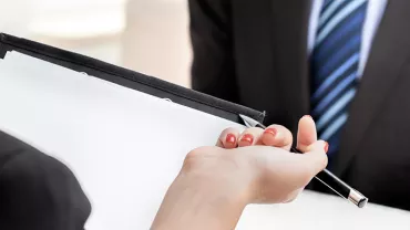 Hands holding a clipboard with a blank paper and a pen.