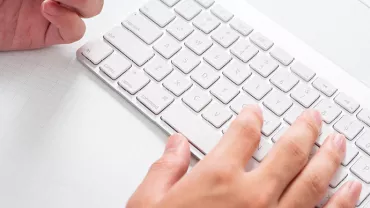 Person typing on a white keyboard.