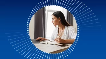 Person writing and using laptop at desk, abstract circular design.