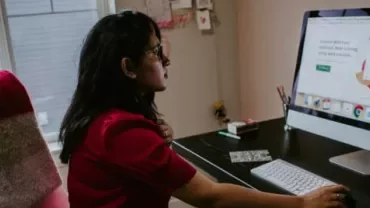 Person seated at desk using a computer.