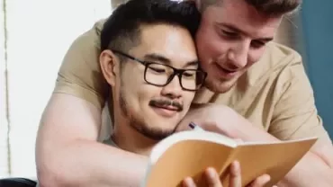 Two people smiling and reading a notebook together.