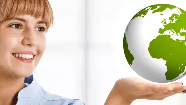 Woman holding a globe in one hand and smiling at it