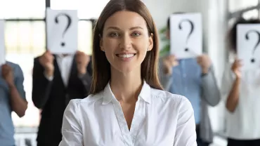 Personne souriante devant d'autres avec des pancartes de point d'interrogation sur le visage.
