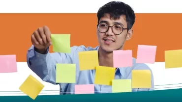 Person arranging colorful sticky notes on a glass surface.