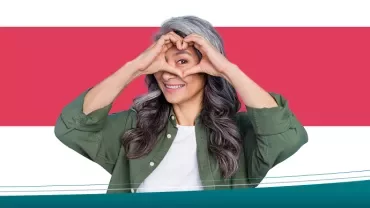Person making a heart shape with hands and smiling.