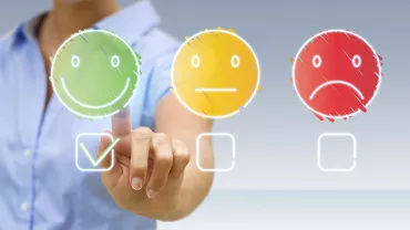 Person selecting a happy face icon on a touchscreen.