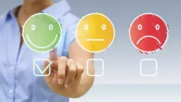 Person selecting a happy face icon on a touchscreen.