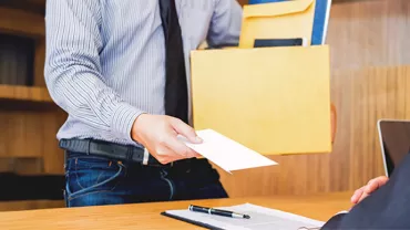 Person holding a folder and envelope in a wooden office setting.