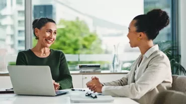 Une manager discute des attentes salariales avec une employée dans une salle de réunion.
