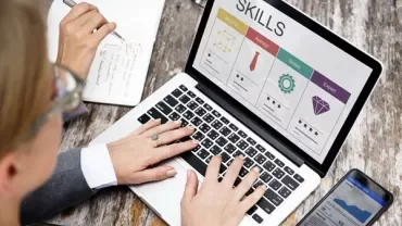 Person working on skills assessment on a laptop at a wooden table.