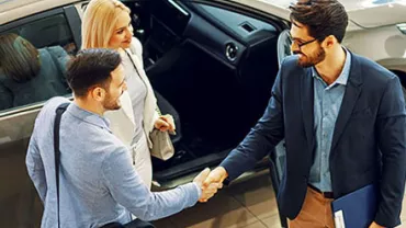 Personnes se serrant la main dans une concession automobile.