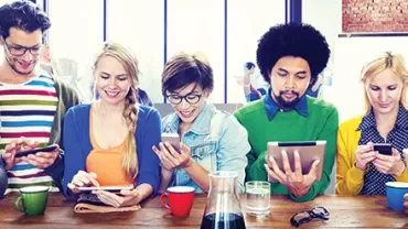 A group of people at a table using phones and tablets.