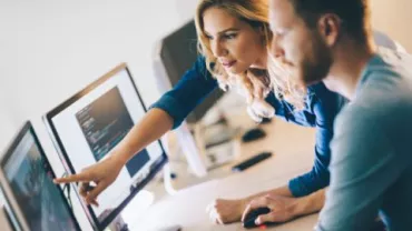 Deux personnes collaborant à un bureau informatique.