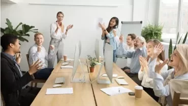 Groep collega's klappen in een vergaderruimte.