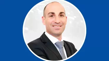 Person in suit smiling against blue background