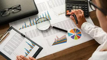 Personne analysant des graphiques financiers avec une calculatrice.
