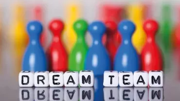Colorful pegs with 'Dream Team' spelled out on dice.