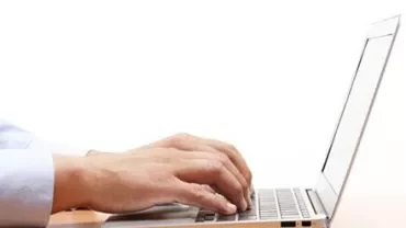Handen typen op een laptoptoetsenbord.