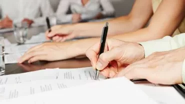 Groupe de personnes écrivant sur des documents à une table.