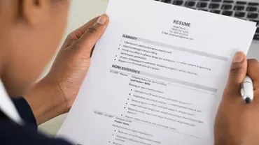 Person holding a resume while writing notes.