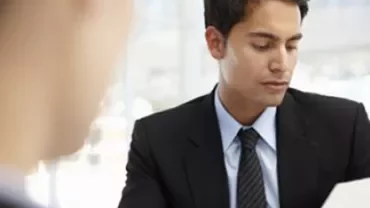 Person in a suit reviewing documents in an office setting.