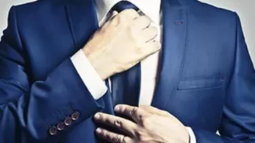 Person adjusting a blue suit and tie.