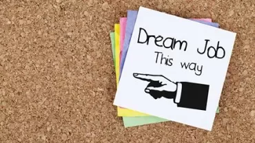 Sign with 'Dream Job' and an arrow on corkboard