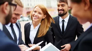 Group of colleagues in business attire having a discussion outdoors.