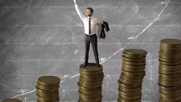 Person standing on stacks of coins with an upward graph in the background.
