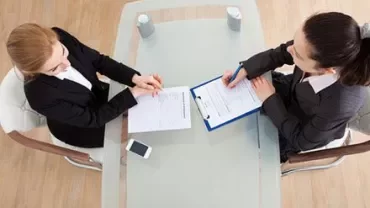 Deux personnes assises à une table, examinant des documents.