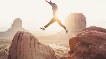 Personne sautant entre les rochers rouges au coucher du soleil