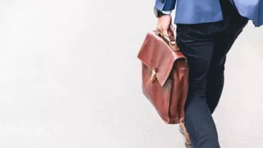 Person walking with a brown leather briefcase.