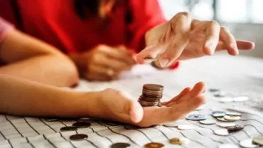 Hands counting coins on a table.