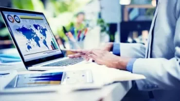 Personne travaillant sur un ordinateur portable avec des graphiques mondiaux.