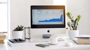 Ordinateur sur un bureau avec graphique à l'écran et plantes à côté.