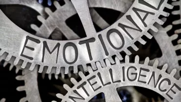Close-up of metal gears engraved with 'Emotional Intelligence'.