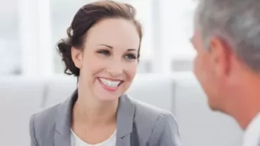 Deux personnes souriantes discutent dans un cadre de bureau.
