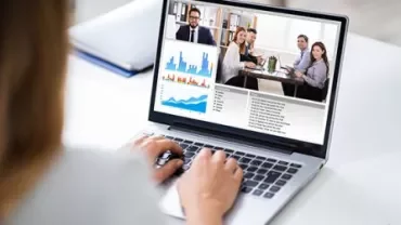 Laptop met een virtuele vergadering en grafieken op het scherm.
