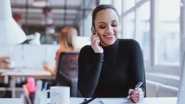 Personne souriante au téléphone dans un bureau.