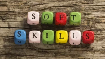 Gekleurde letterblokjes spellen 'soft skills' op een houten achtergrond.