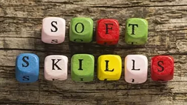 Colorful letter blocks spelling 'soft skills' on wood.