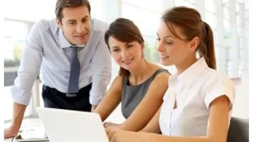 Drie mensen werken samen met een laptop.