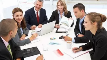 Groupe de personnes en réunion avec graphiques et ordinateurs.