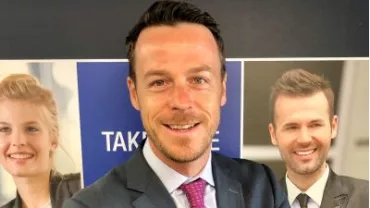 Personne souriante devant des affiches promotionnelles.