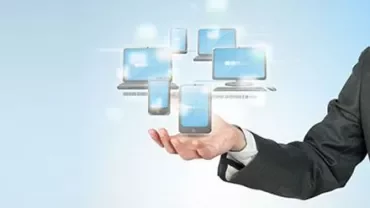 Hand holding digital devices with glowing screens.