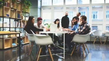 Groupe de collègues collaborant autour d'une table dans un bureau moderne.