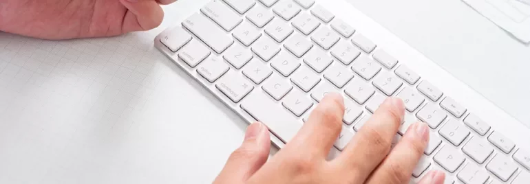 Person typing on a white keyboard.