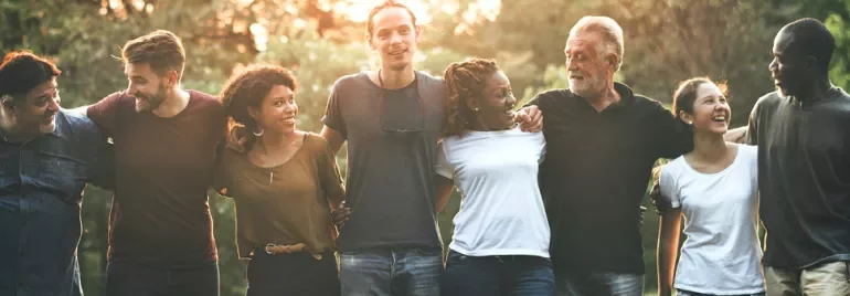 Groupe de personnes debout ensemble à l'extérieur, se souriant.