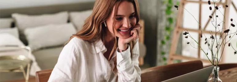 Person smiling while using a laptop at home.